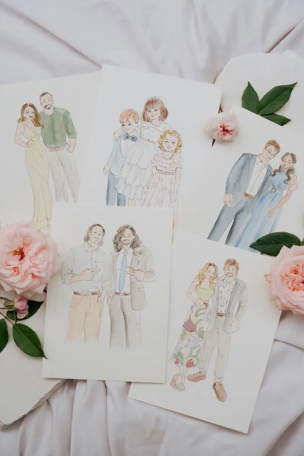 Flat lay of soft watercolour guest portraits of couples and a family among pink garden roses, by Adore by Lissy