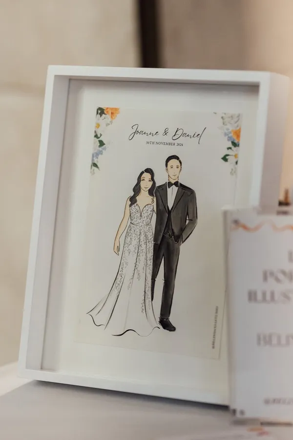 Framed watercolour illustration of a bride and groom in a lace gown and tuxedo with floral corners, by Belinda Xia Studio